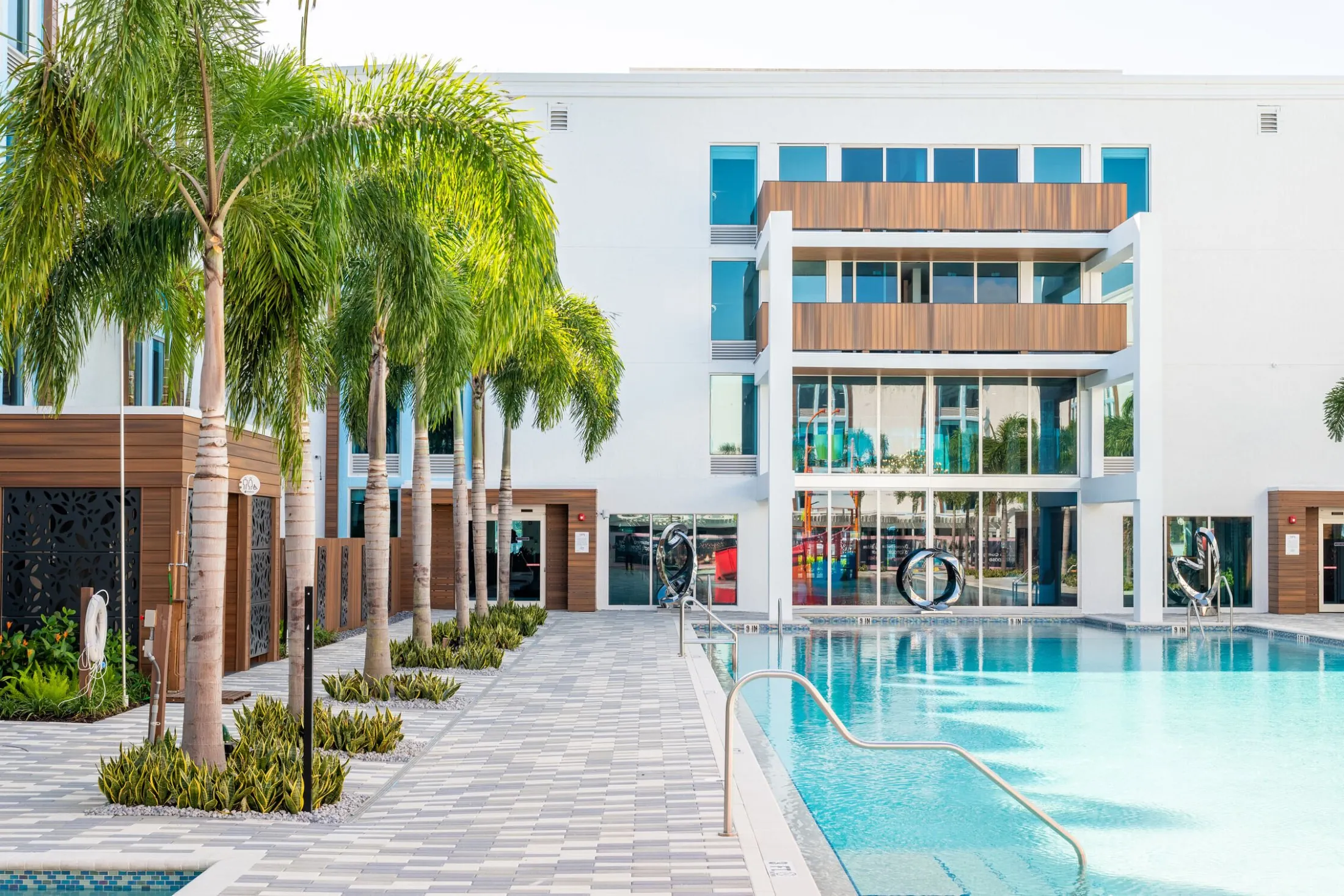 A hotel pool area with palm trees and a building in the background.