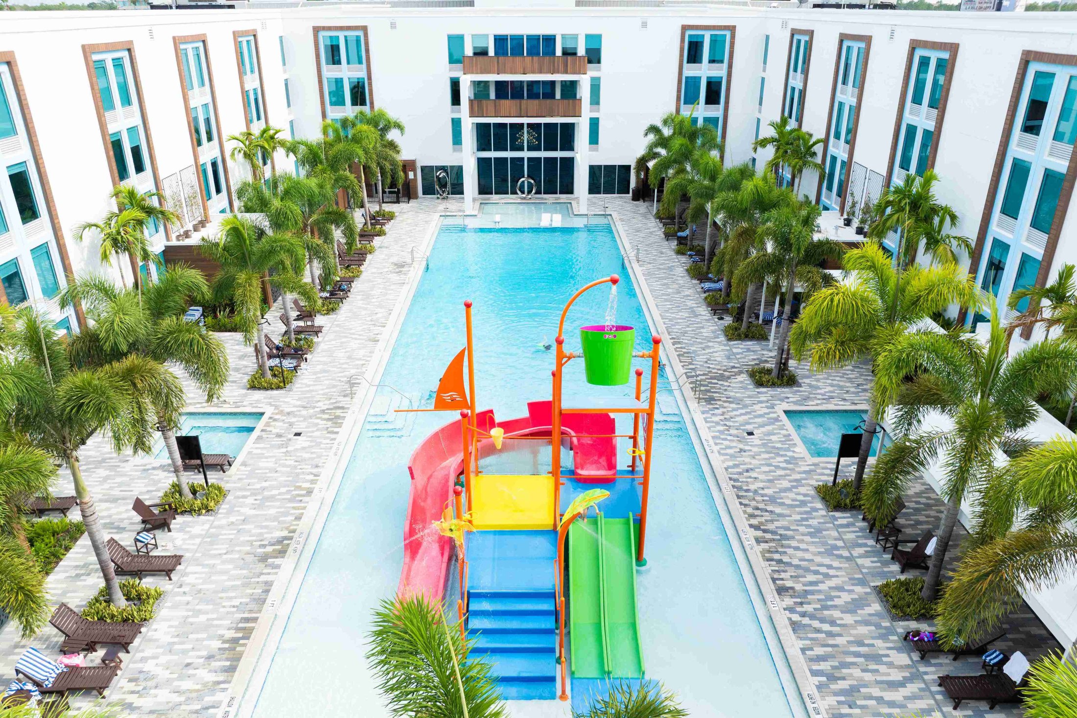 A large swimming pool with a water slide and palm trees