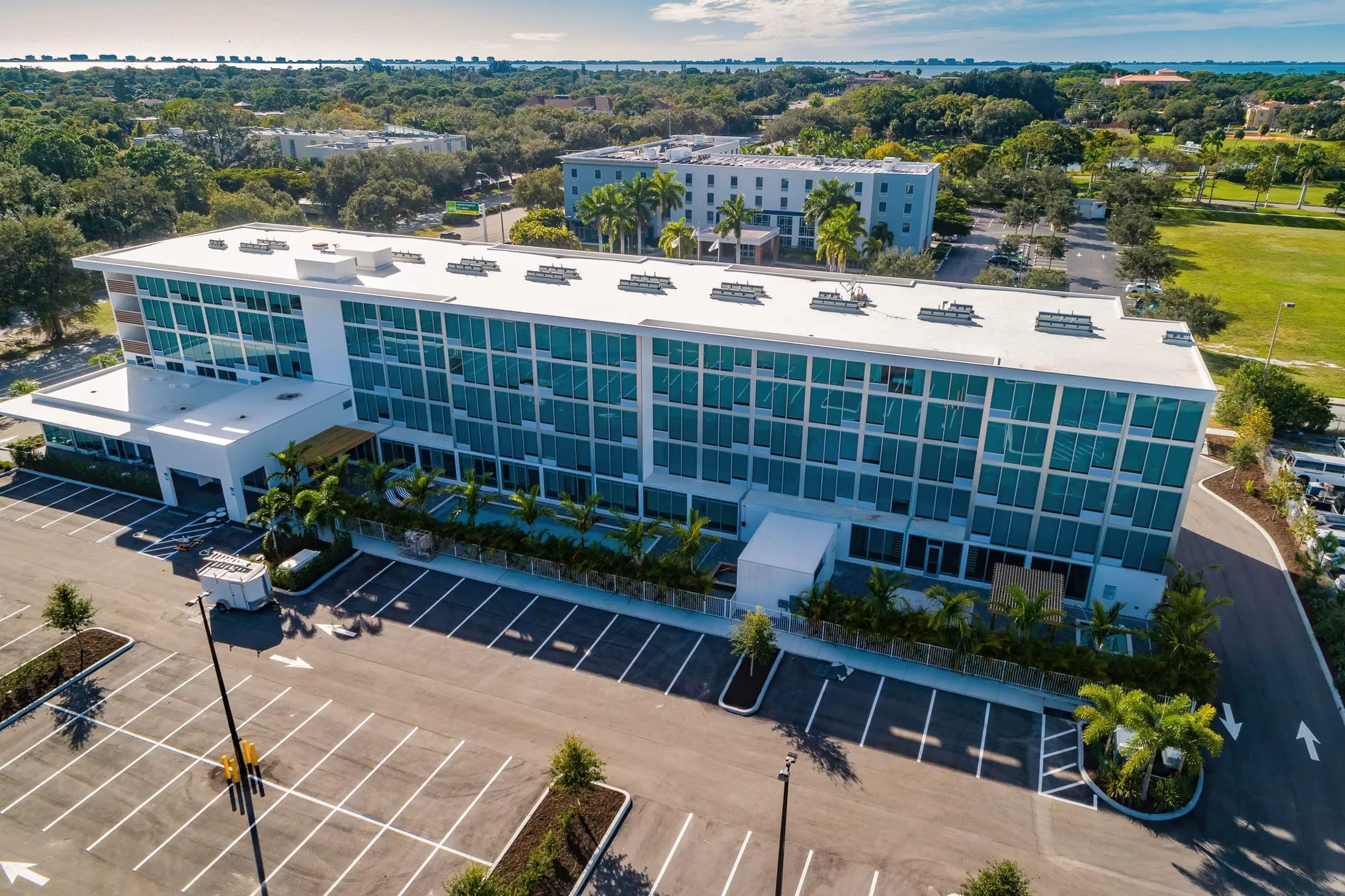 An aerial view of a large white building with many windows and a parking lot.
